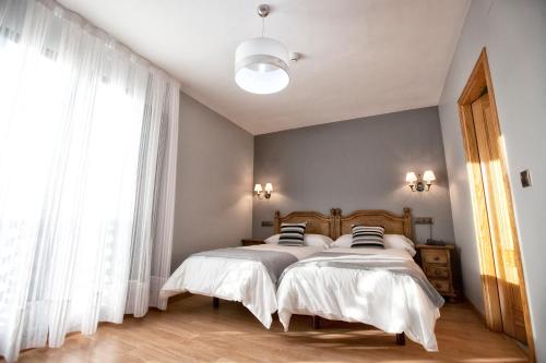 Un dormitorio con dos camas y una gran ventana. en Hotel Santa Cruz, en Cangas de Onís