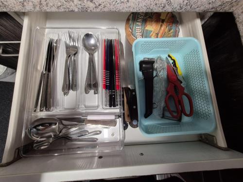 a drawer filled with utensils and a plastic container at Spacious cellar studio surrounded by mountains and lake in Schwanden