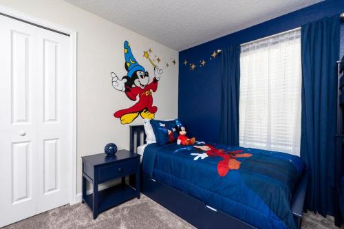 a bedroom with a blue bed with a disney character on the wall at Stunning 5 Bd w/ Pool Close to Disney 2905 in Kissimmee