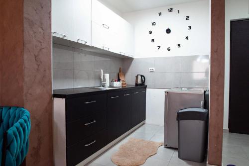 a kitchen with black cabinets and a clock on the wall at Apartman Royal 3 in Doboj