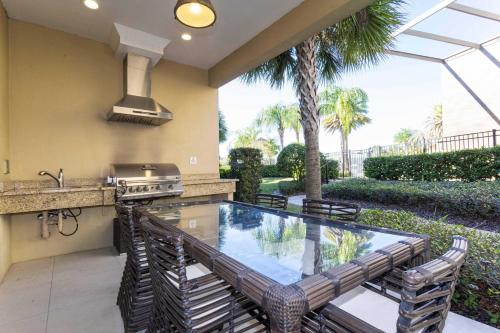 a swimming pool in a patio with a grill and chairs at Gorgeous 4 Bd Close to Disney @ Magic Village 3114 in Orlando