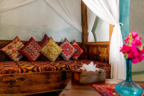 a bedroom with a bed with pillows and a vase of flowers at Casa Paradis Boutique Hotel in Jambiani