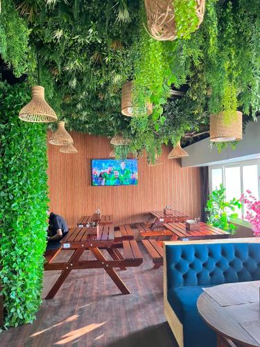 a restaurant with tables and a couch and plants at Hotel EDEN in Kārwār