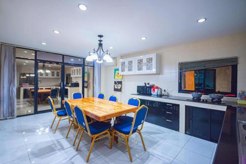 a kitchen with a wooden table and blue chairs at Soi 15 Thappraya Pool villa- 5km to Jomtien beach in Pattaya