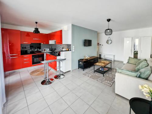 - un salon et une cuisine avec des placards rouges et un canapé dans l'établissement Studio, Terrasse, Confort & Emplacement Idéal !, à Montévrain