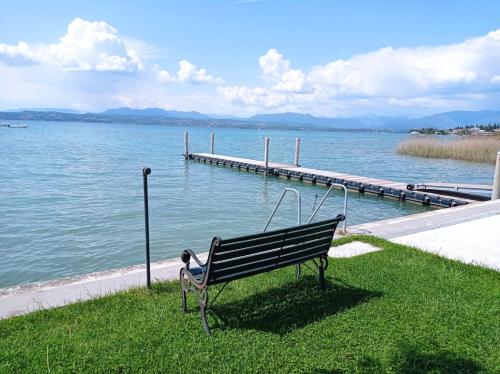 a bench sitting on the grass next to a dock at Super Location front lake in Sirmione