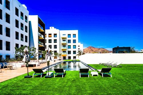 a building with chairs and a pool in the grass at Casa Flor Cabo Your Private Oasis in Cabo San Lucas