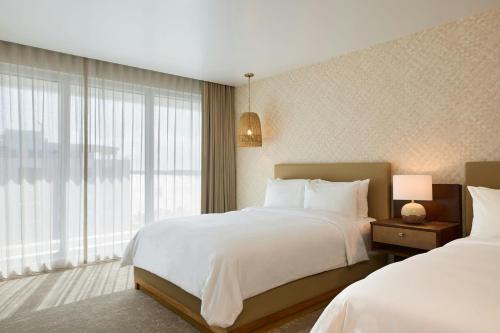 a bedroom with two beds and a large window at Casa Costera, Isla Verde Beach, Apartments by Marriott Bonvoy in San Juan