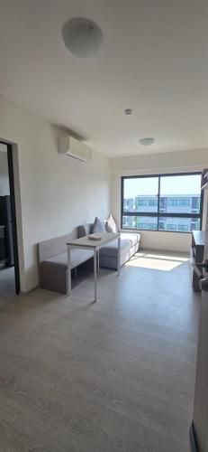 a living room with a couch and a large window at Grene Donmueng in Thung Si Kan