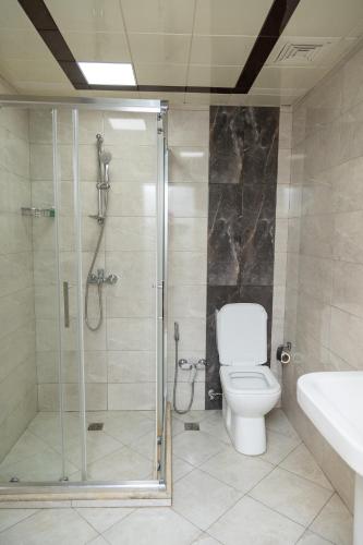a bathroom with a shower and a toilet and a sink at Flamingo Hotel in Baku