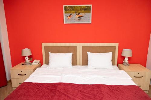 a red bedroom with a bed with white sheets and two lamps at Flamingo Hotel in Baku