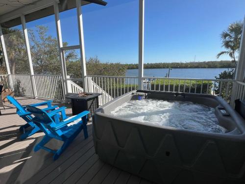 a hot tub on a deck with two blue chairs at Private Bayfront Beach House with Dock, Steps to Beach and Restaurants in Englewood