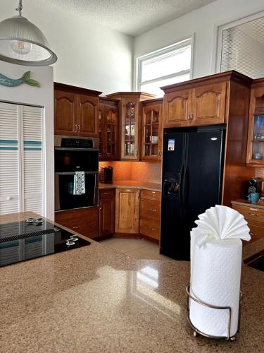 a kitchen with a black refrigerator and wooden cabinets at Private Bayfront Beach House with Dock, Steps to Beach and Restaurants in Englewood