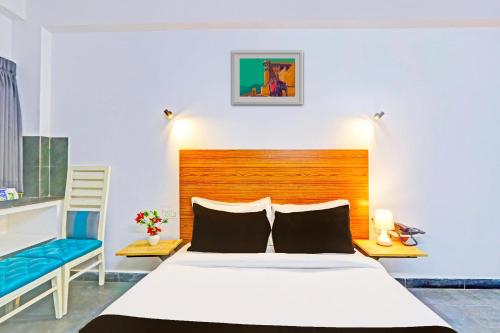 a bedroom with a bed and a blue chair at Collection O De Alphabet Hotel UMCC in Hyderabad