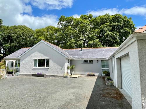 a white house with a driveway and a garage at Allt Lwyd - Peaceful & Tranquil Setting in Bangor