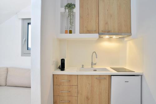a kitchen with wooden cabinets and a sink at Niriis Studios Aktaia & Glauke Batsi in Batsi