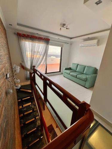 a living room with a green couch and a staircase at Thea appartment in Xgħajra