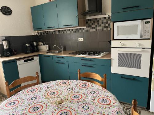 une cuisine avec des armoires bleues et une table avec une nappe dans l'établissement Gîte Les Lilas, à Champlecy