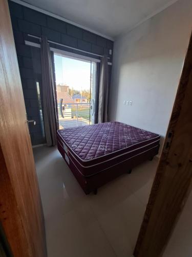un letto in una camera con una grande finestra di S2 - Residencial Soulmar Balneário Gaivota - SC - Village Dunas Norte - 1,5 quadra do mar a Balneário Gaivotas