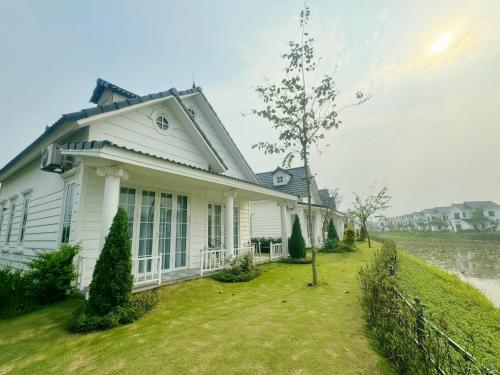 a white house with a fence in the yard at Phòng Đôi tại Happy Villa - Vườn Vua gồm ăn sáng và ăn tối in Ðồng Phú
