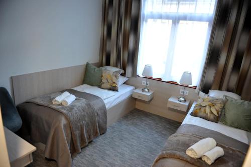 a small room with two beds and a window at Hotel Három Gúnár in Kecskemét