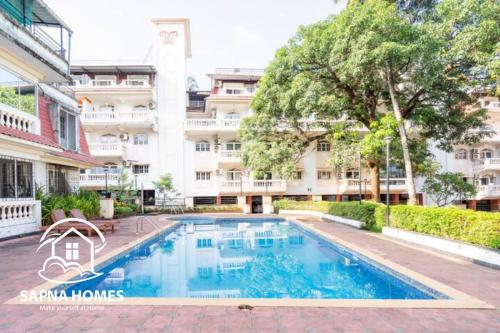 a swimming pool in front of a building at Sapna Homes 4BHK Penthouse, 5min to Beach in Colva