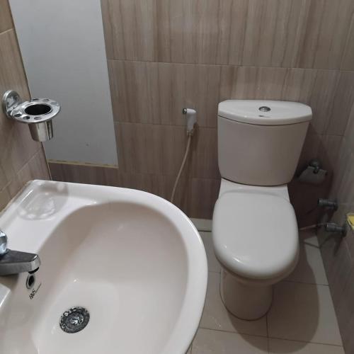 a bathroom with a white toilet and a sink at Janima Home in Gampaha
