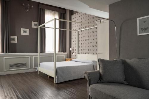 a bedroom with a bed and a chair and a couch at Maxxim Hotel & Loft in Ferrara