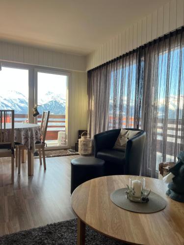 a living room with a table and a room with mountains at Magnifique appartement avec une Superbe Vue panoramique in Veysonnaz