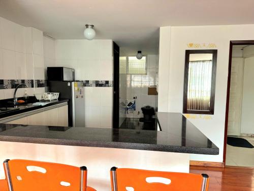 a kitchen with a black counter top and orange chairs at Oporto 83 in Bogotá