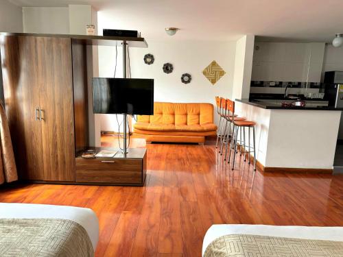a living room with a television and a couch and a kitchen at Oporto 83 in Bogotá