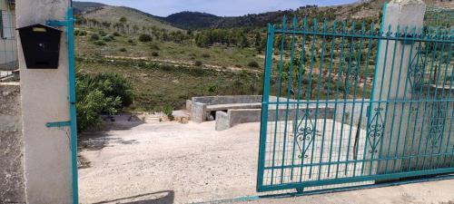 a blue gate with a bench in front of a mountain at Kineta Farmhouse in Kineta