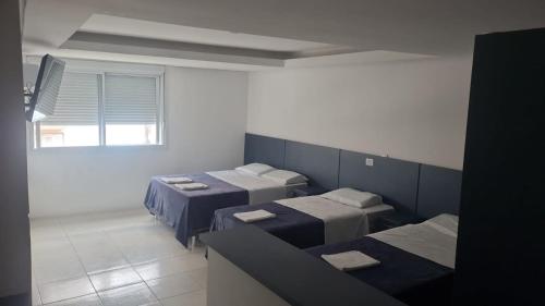a room with three beds and a window at HOTEL DO CENTRO 100m SANTA CASA, ASSEMBLEIA E UFRGS, PROXIMO AO ARAUJO VIANA, PET'S FRIENDLY!!! in Porto Alegre