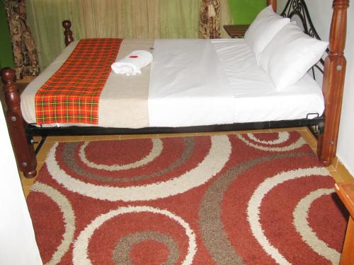 un letto con lenzuola e cuscini bianchi su un tappeto di Lulu's Guest House a Nairobi