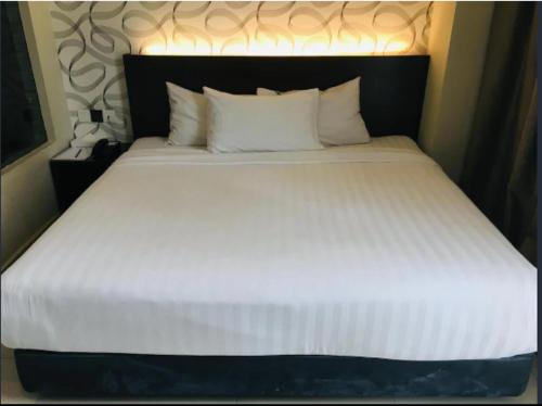a large white bed with a black headboard and pillows at Izumi Hotel Bukit Bintang Kuala Lumpur in Kuala Lumpur