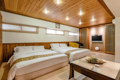 a room with two beds and a table and a tv at 宜蘭小綠丘民宿 in Luodong