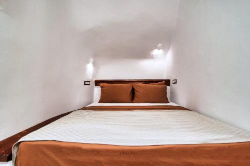 a small bedroom with a bed in a white room at Ducato Dream jaccuzi Suite Imerovigli Santorini in Imerovigli
