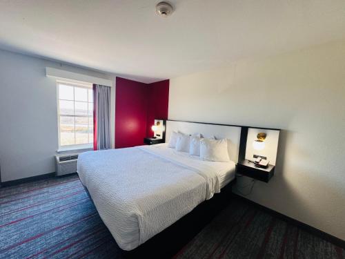 a hotel room with a large bed and a red wall at Ramada by Wyndham Sparta/At Speedway in Sparta