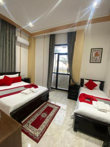 a bedroom with two beds with red pillows and a window at Hotel Biarritz in Tangier