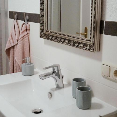 a bathroom sink with a mirror and two cups on it at Ferienhof am Ipf in Bopfingen
