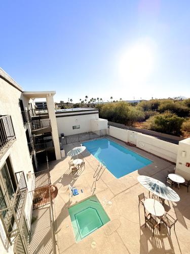 a swimming pool with chairs and umbrellas next to a building at Studio 6 Suites Tucson, AZ Airport Kino Sports Complex in Tucson