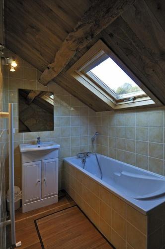 La salle de bains est pourvue d'une grande baignoire et d'un lavabo. dans l'établissement Gîte de Caractère la Grange, à Buzeins