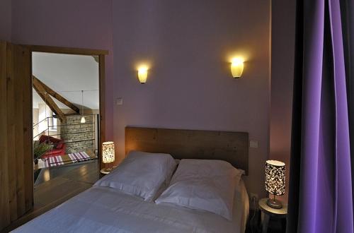 - une chambre avec un lit aux murs violets et deux lumières dans l'établissement Gîte de Caractère la Grange, à Buzeins