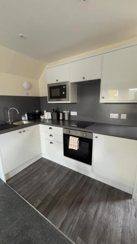a kitchen with white cabinets and a black counter top at The Waverley Inn Holiday Homes in Inverness