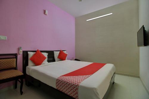 a bedroom with a bed and a chair and a television at Hotel O Manu Residency in Bengaluru