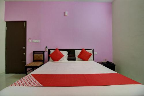 a bedroom with a large bed with red pillows at Hotel O Manu Residency in Bengaluru