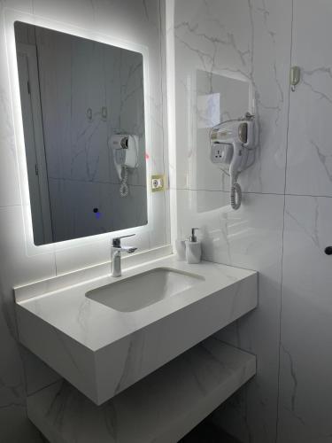 a white bathroom with a sink and a mirror at Guesthouse Butrinti in Ksamil