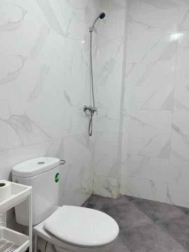 a white bathroom with a toilet and a shower at Playa Surf House in Tamraght Ouzdar