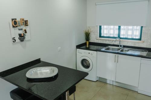 a kitchen with a sink and a washing machine at Comfort Zone beach apartment in Quarteira