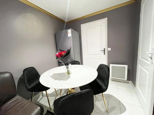 une salle à manger avec une table blanche et des chaises noires dans l'établissement Bel appartement Épinay sur Seine près du stade de France, à Épinay-sur-Seine